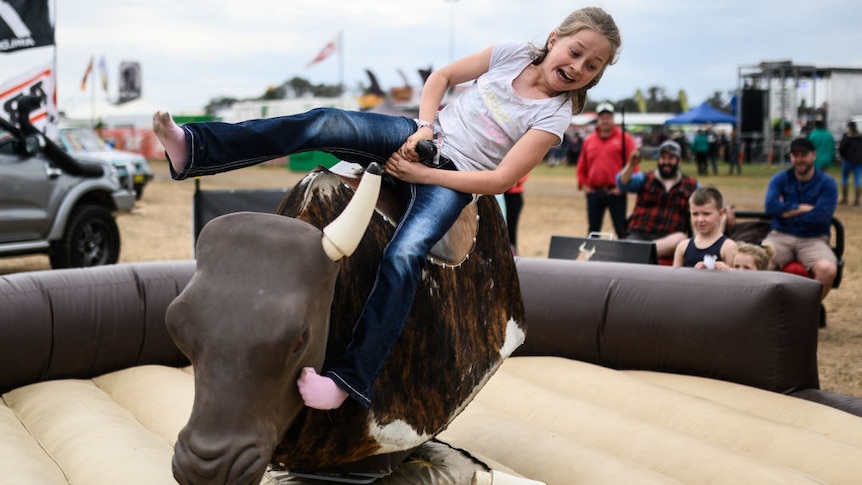 a young girl riding a mechanical bull in Deniliquin