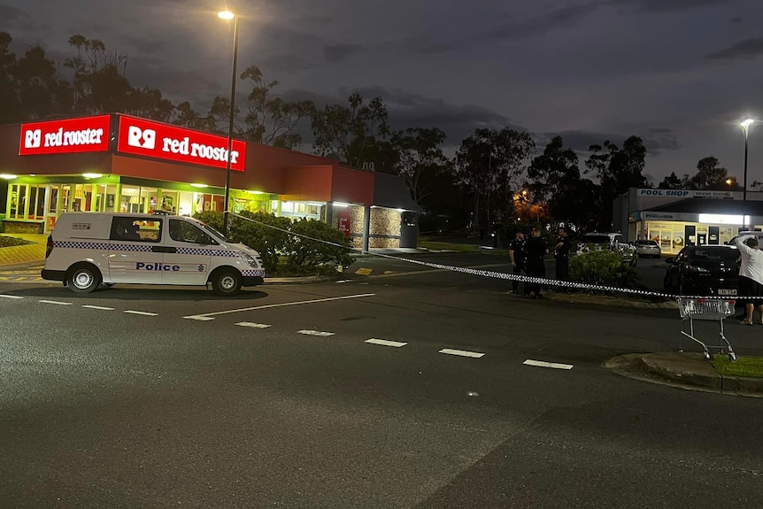 police van and crime scene tape block of the entrance to a Red Rooster.