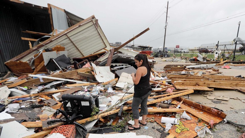 Woman stands amid debris