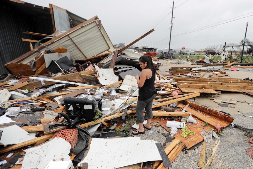 Woman stands amid debris