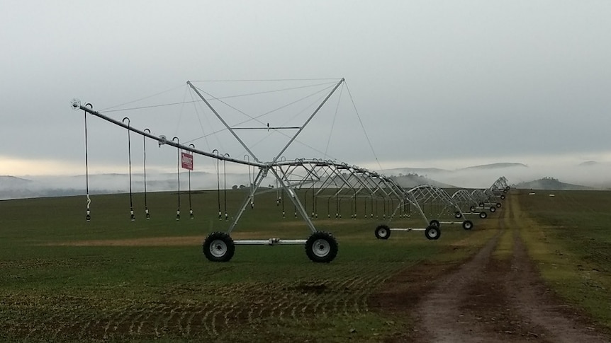 An irrigation pivot sitting in a paddock on green grass.