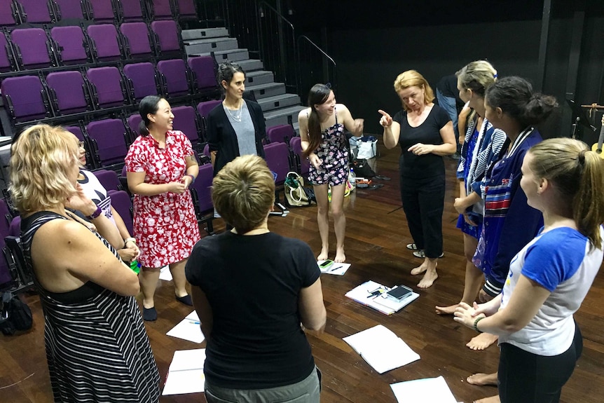 The all-female cast stand in a circle inside a Darwin theatre