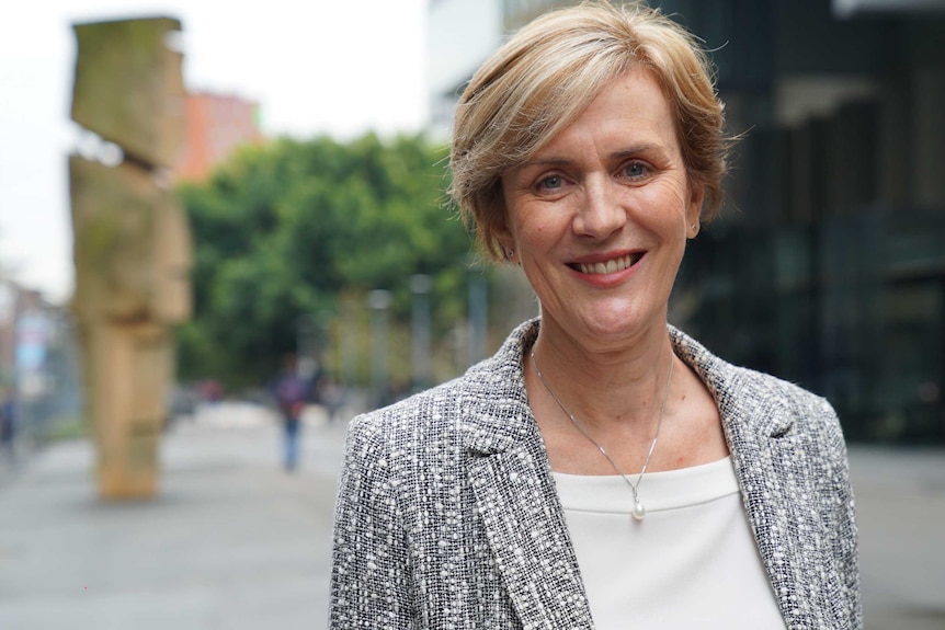 Bereavement counsellor Dr Elizabeth Mann standing outside in Sydney CBD, wearing tweed blazer.