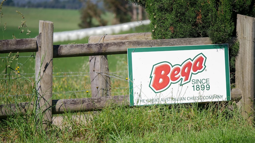 a sign of Bega cheese on a fence with green grass around