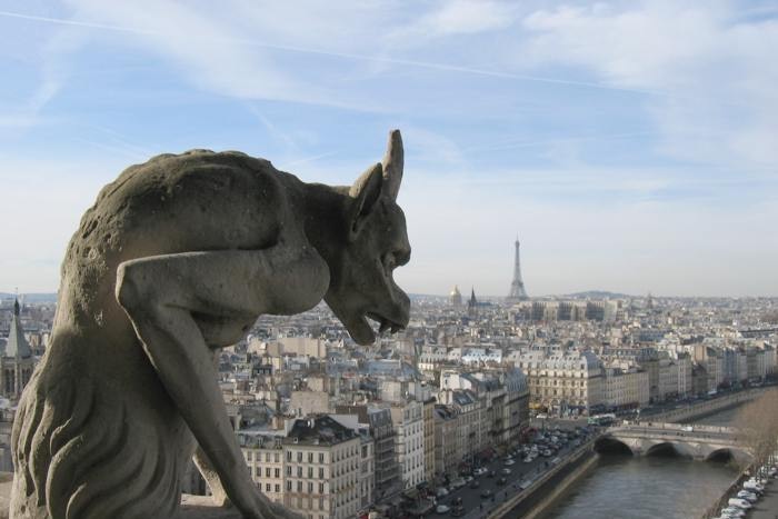 A view of buildings in Paris behind a gargoyle on the roof of Notre Dame cathedral