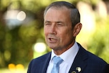 A man wearing a suit and tie speaks at a press conference. 