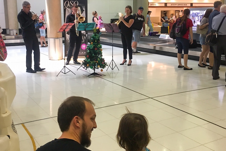 The trio perform at the luggage carousel at the domestic airport.