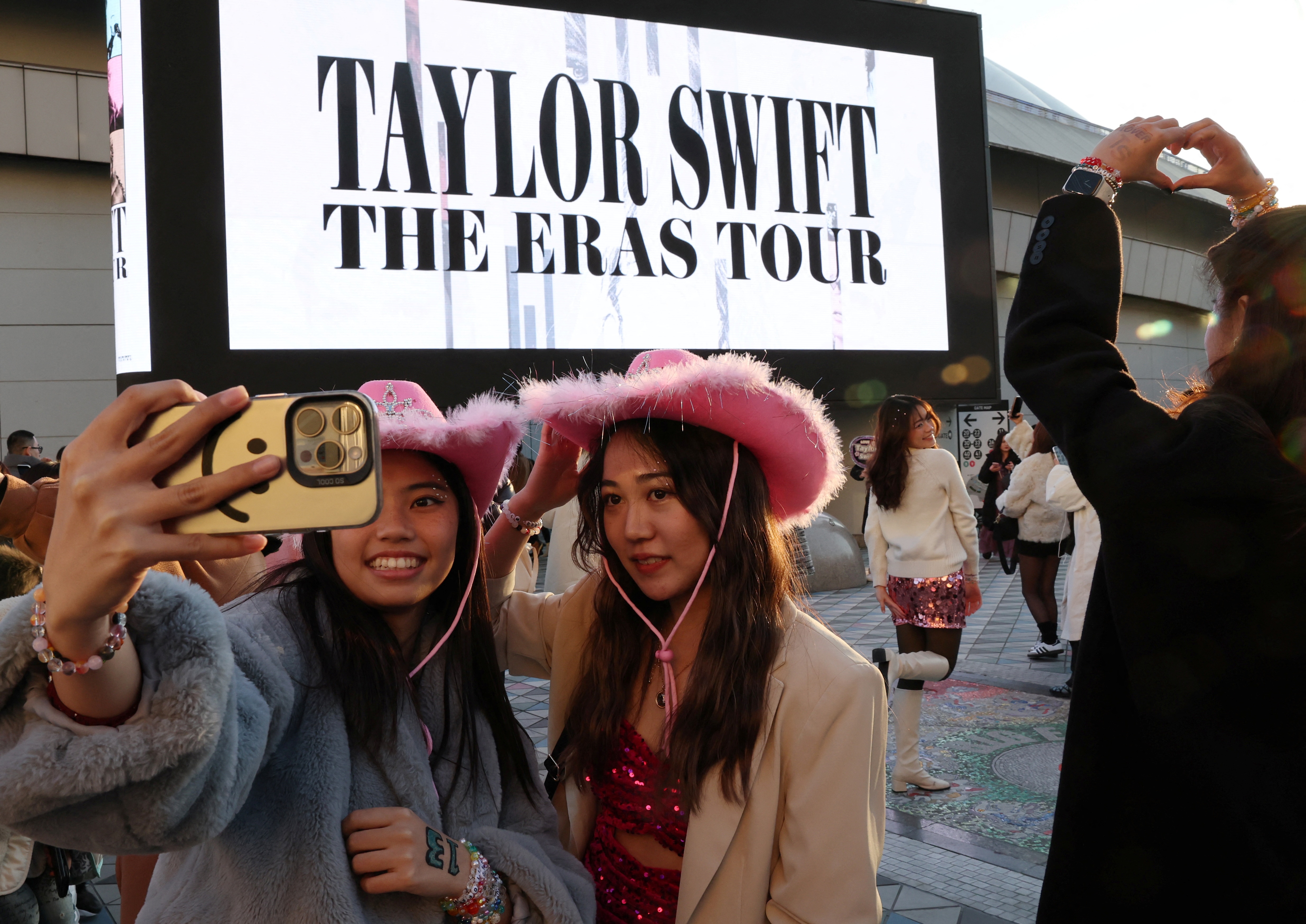 Japanese fans of Taylor Swift take a selfie before entering the venue for Taylor Swift's international tour