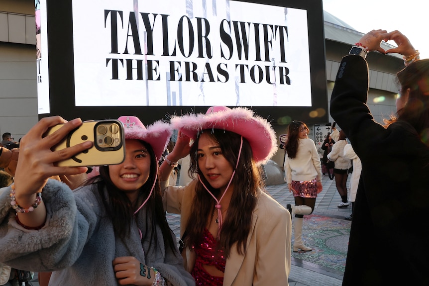 Japanese fans of Taylor Swift take a selfie before entering the venue for Taylor Swift's international tour