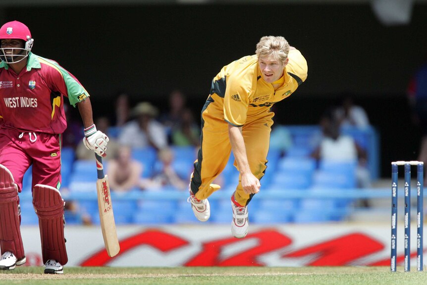 Shane Watson follows through from bowling a cricket delivery as West Indies batsman Brian Lara looks on.