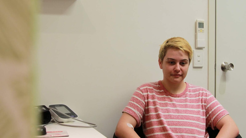 A transgender Darwin teenager sits in the waiting chair in a doctor's office.