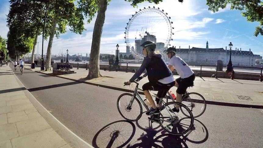 People cycling along a path with the London Eye in the background.