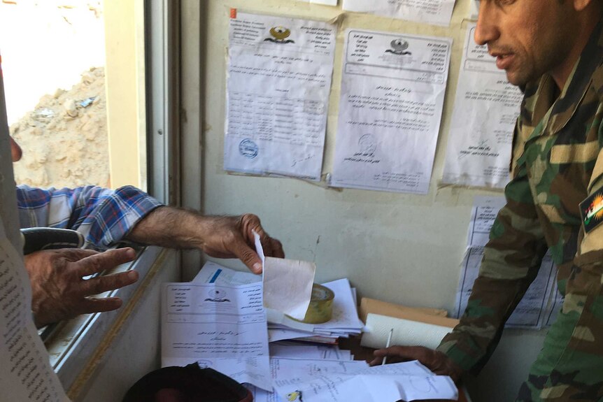 A man shows his permission papers to a Kurdish solider at checkpoint in northern Iraq.