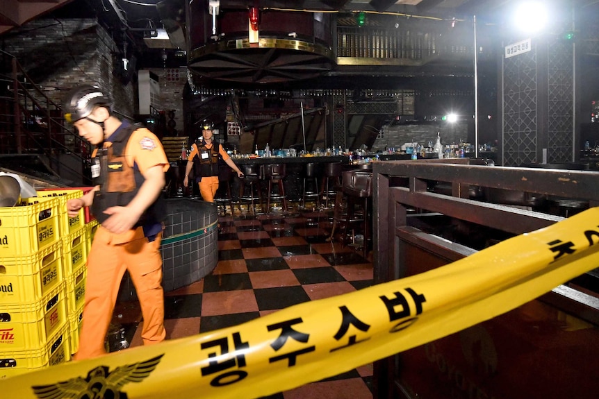 Two rescuers rush past inside a deserted nightclub