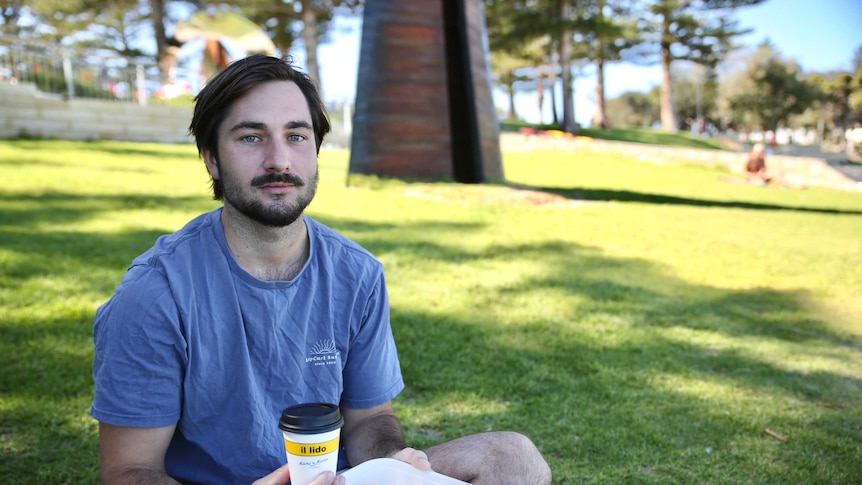 Cameron McQuie, 24, has a takeaway coffee on the beach.