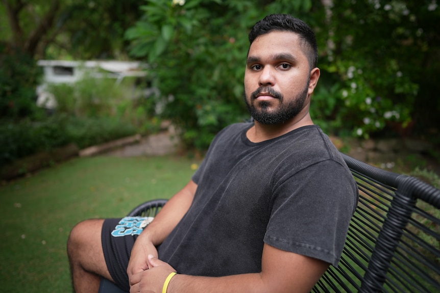 Leeroy sitting on a park bench in a leafy park, looking seriously at the camera.