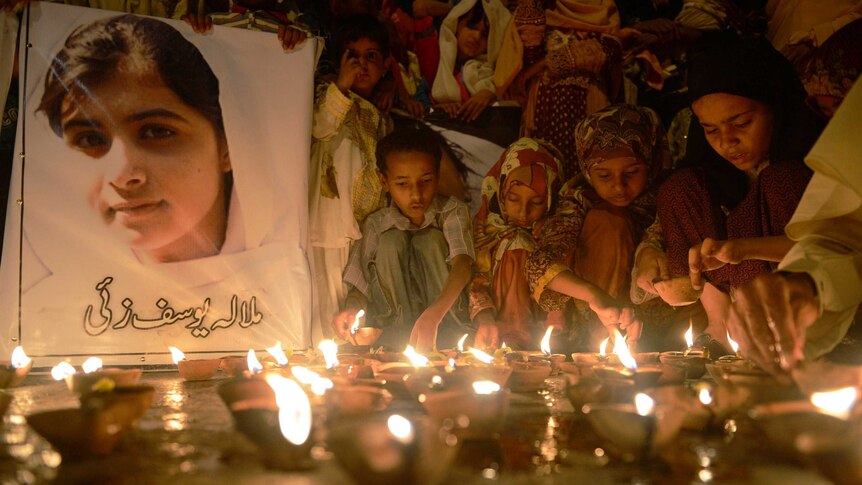Pakistani children place oil lamps next to a photograph of child activist Malala Yousafzai.