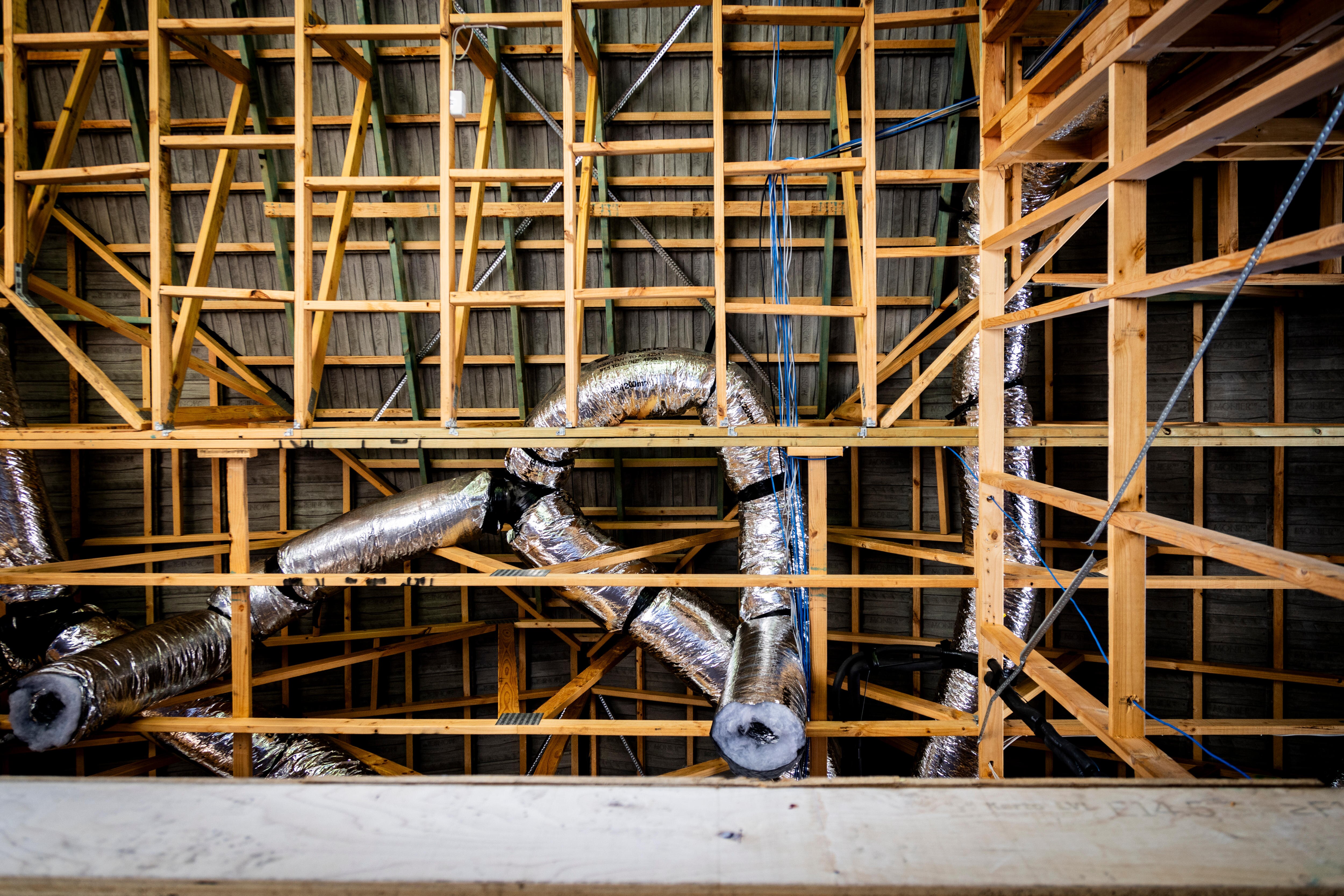 A cross-cross of wooden beams and foil pipes can be seen.