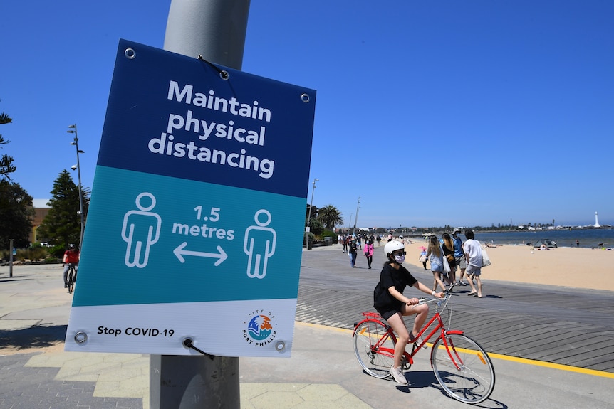 Social distancing signage is seen along St Kilda beach.