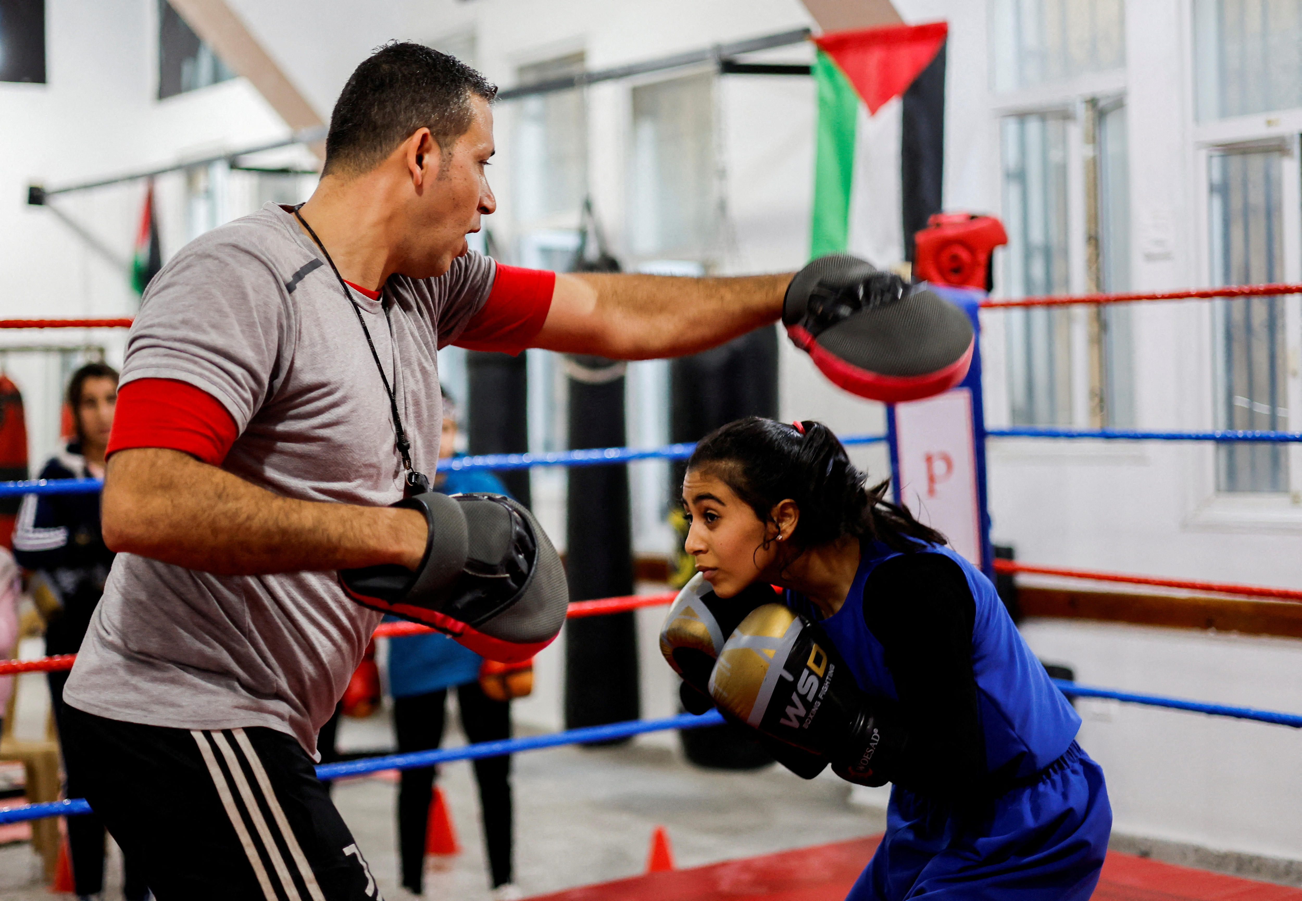 A man punches the air as a girl ducks holding her boxing gloves near her face. 