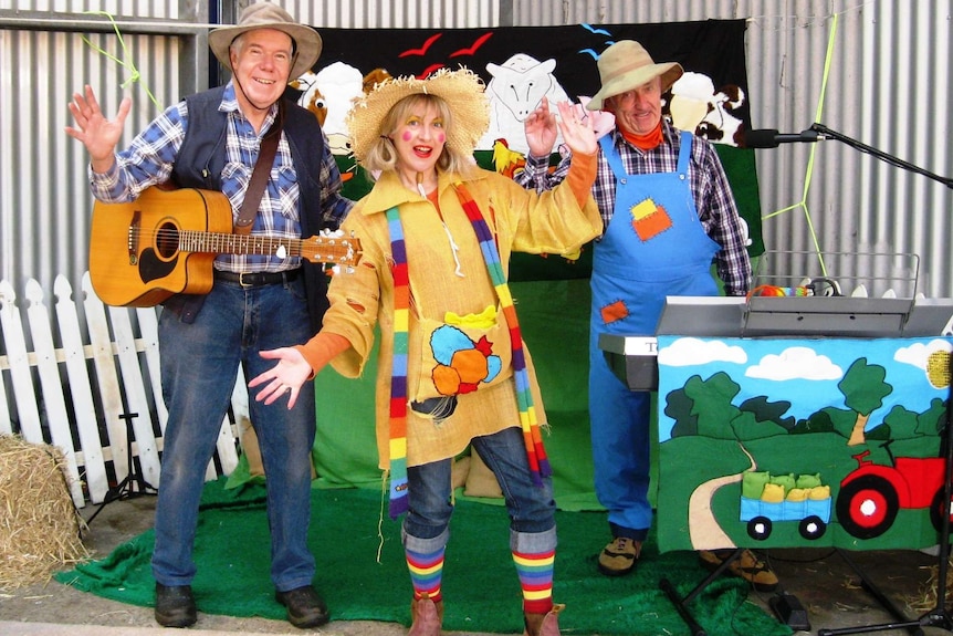 A woman dressed as a scarecrow, with two men either side playing guitar and keyboard