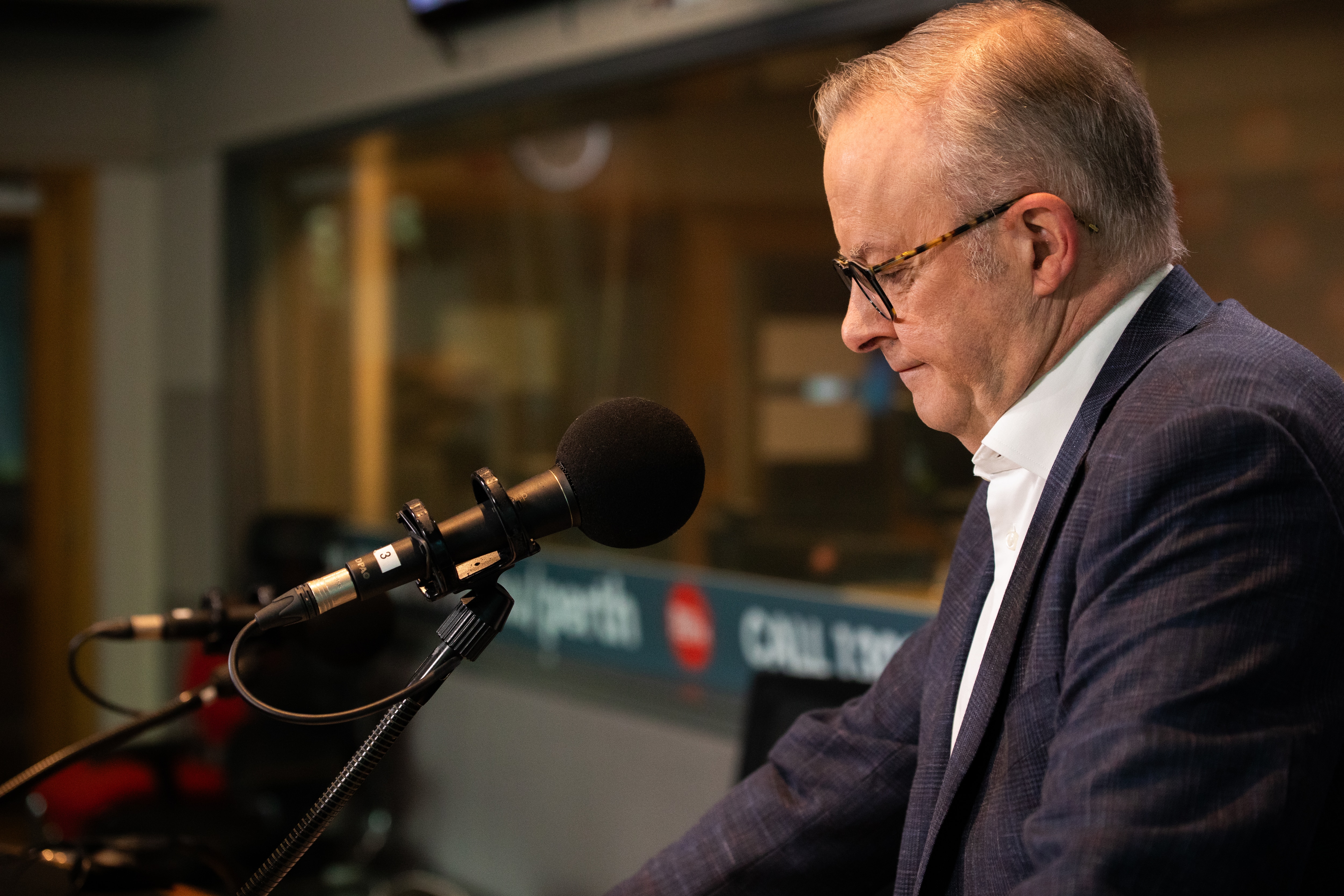 Anthony Albanese stands in front of a microphone looking down.