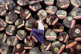 Worker draws paint markings on wood logs being prepared for export