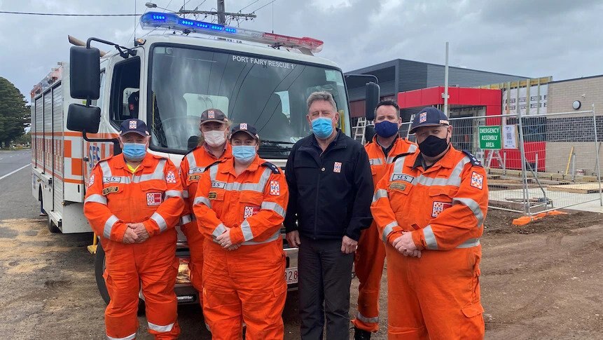 Port Fairy SES team pose in front of rescue truck and local HQ site under construction