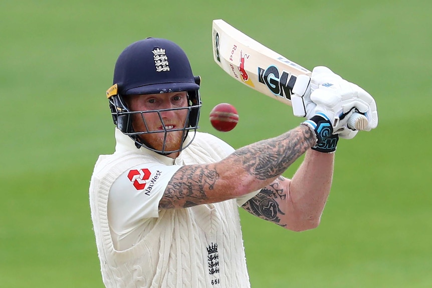 Ben Stokes, wearing a batting helmet grits his teeth and swings his cricket bat at the ball