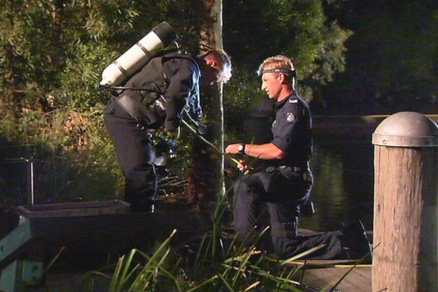 A police diver searches for the bodies of two men in a lake at Mill Park