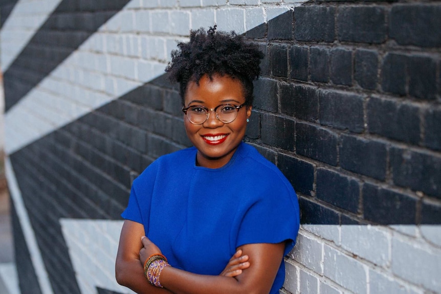 Santilla Chingaipe, a woman of colour who finds it hard to find makeup to match her skin tone, poses in front of a brick wall