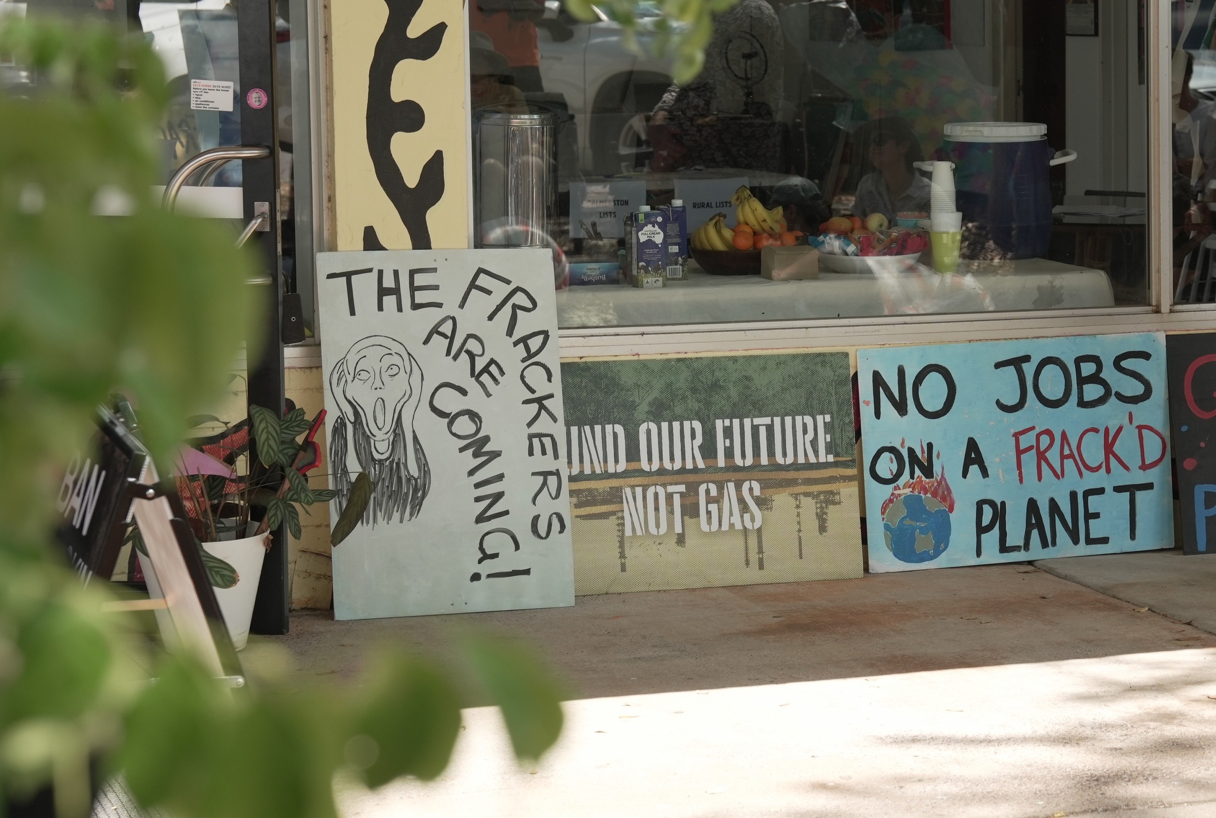 Hand-made signs lined up next to one another, they read: 'THE FRACKERS ARE COMING', and 'NO JOBS ON A FRACK'D PLANET'.