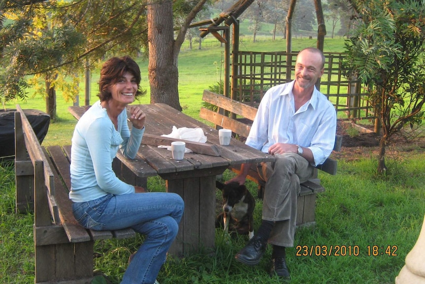 A woman and man sitting at a table in a backyard.