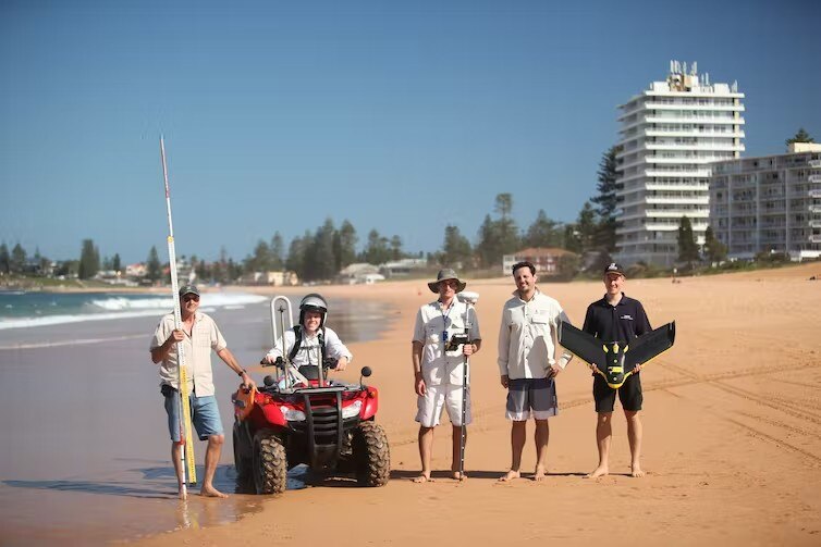 A group of men with equipment stand on a beach