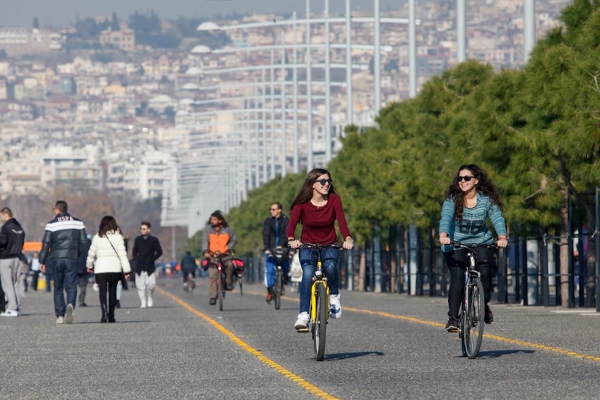 Cyclists ride and pedestrians walk along the seafront of Thessaloniki, Greece.