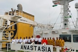 Crew stand on the deck of the bulk carrier Anastasia. It is a large ship and they seem very small by comparison.