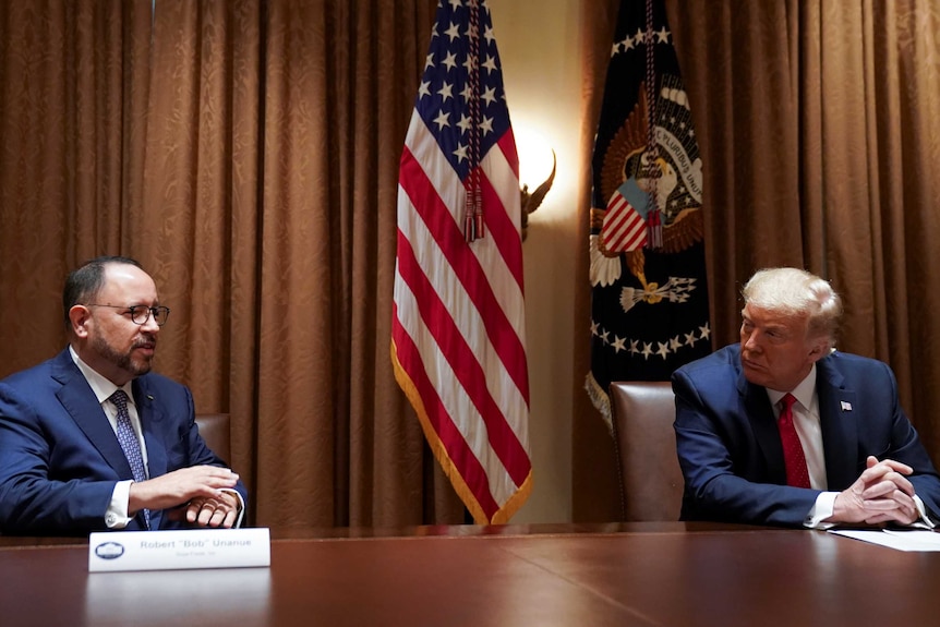 US President Donald Trump listens to remarks from Robert Unanue, CEO of Goya Foods as the pair sit at a desk.