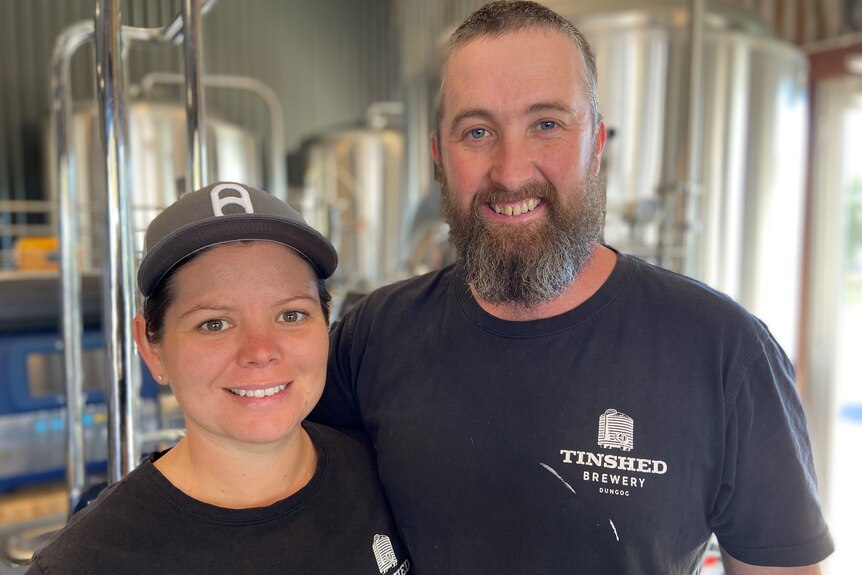 woman and man inside a brewery, smiling at the camera