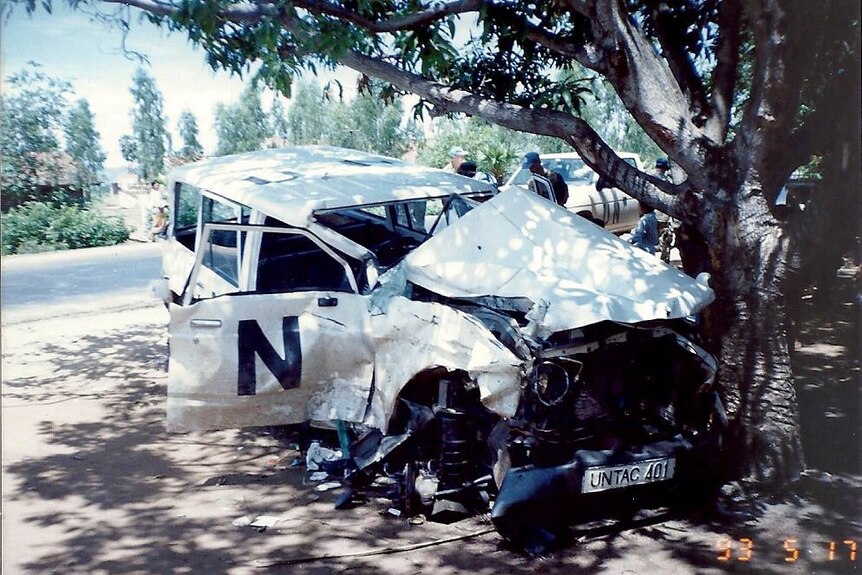 A mangled white United Nations four wheel drive has crashed into a tree on the side of the road