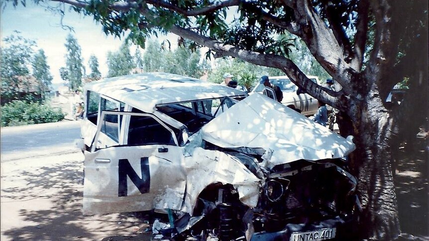 A mangled white United Nations four wheel drive has crashed into a tree on the side of the road