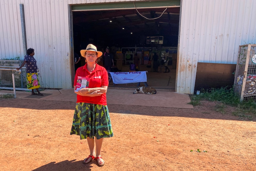 A woman stands with her arms folded in front of a shed where remote polling is taking place. 