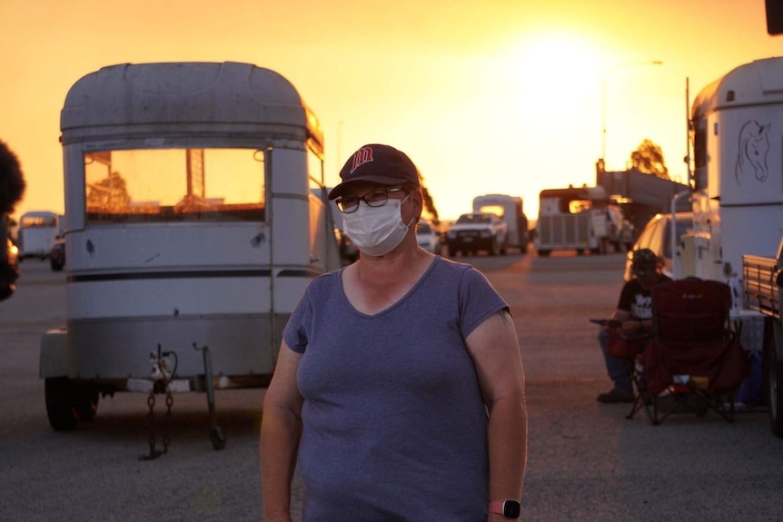 Bullsbrook resident Sharleen Hall pictured standing in front of horse floats and a bright yellow sky.