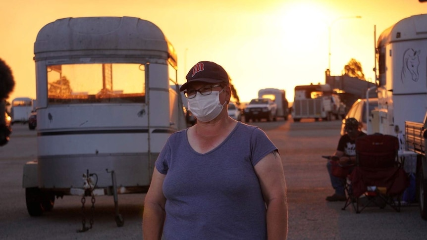 Bullsbrook resident Sharleen Hall pictured standing in front of horse floats and a bright yellow sky.