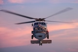 A helicopter flying in the air at sunset.