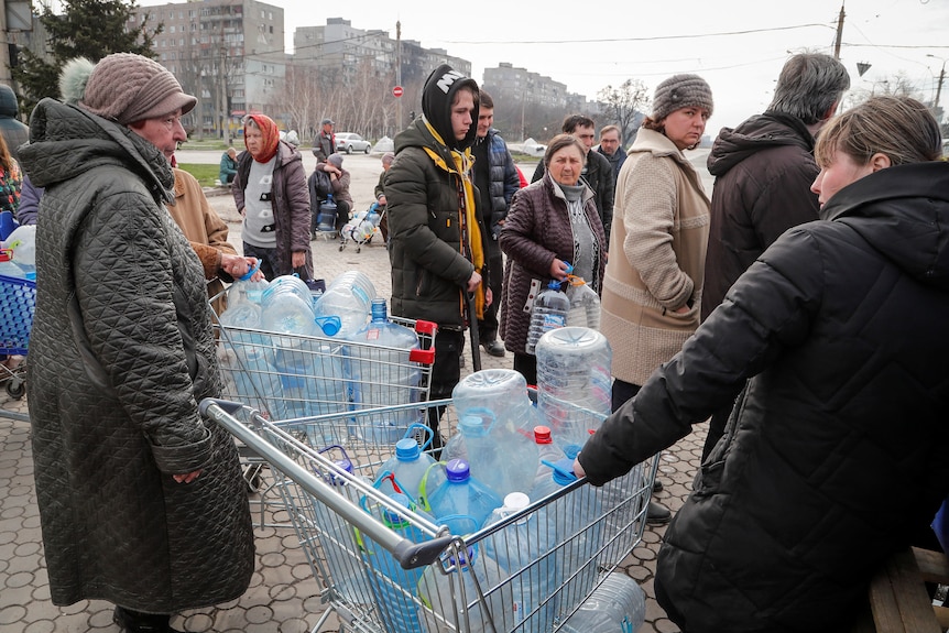 Residents queue to get water, some with containers in shopping trolleys