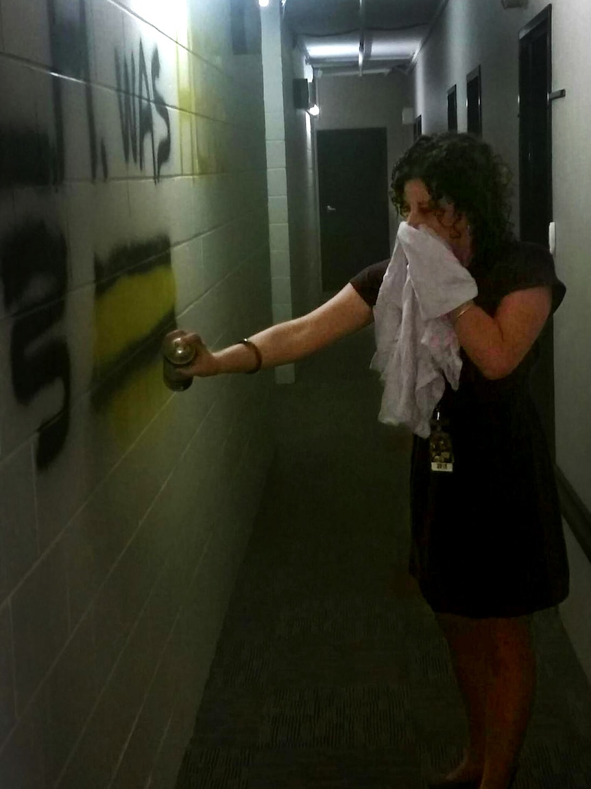 A woman stands in a dress with a spray paint can.