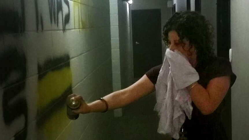 A woman stands in a dress with a spray paint can.