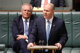 Josh Frydenberg stands at a podium and is photographed mid-speech, while Prime Minister Scott Morrison stands behind him.