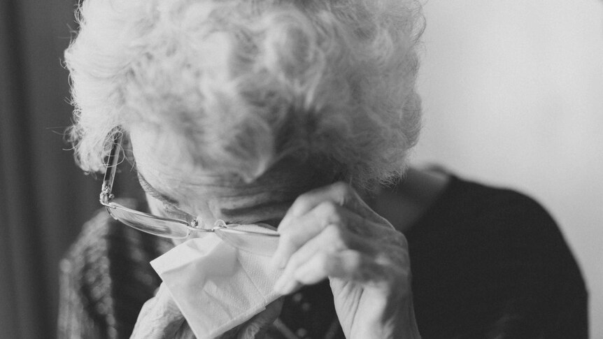 An older lady wiping her eyes with a tissue