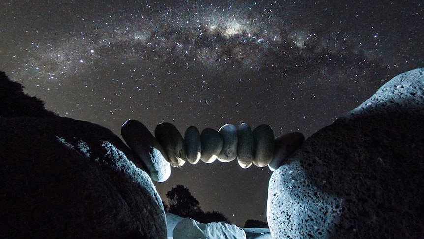 A rock arch under a starry sky.